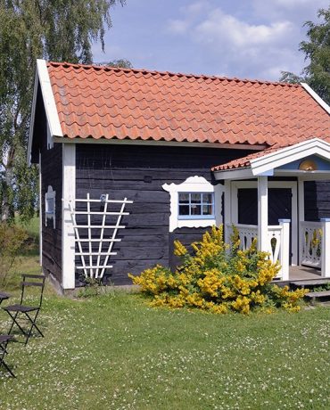 Sommerhaus Kleines braunes Häuschen an einer grünen Sommerwiese.